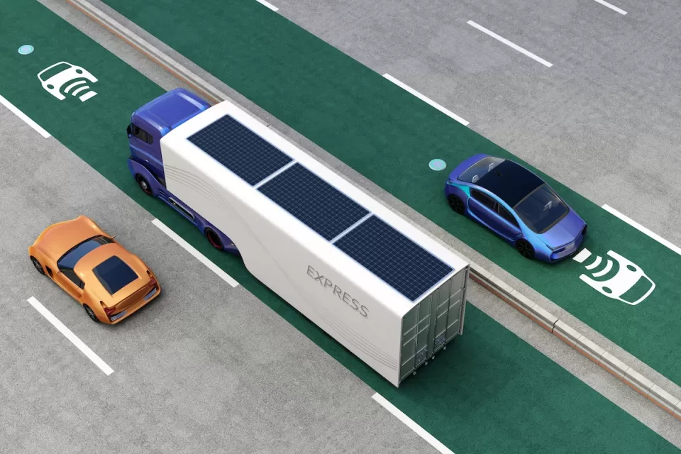 Rendering of truck and cars driving on green electric vehicle charging roadway lane.